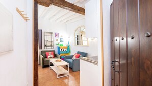 Un salon chaleureux avec un plafond en bois, un canapé, une table basse et des coussins aux couleurs vives.