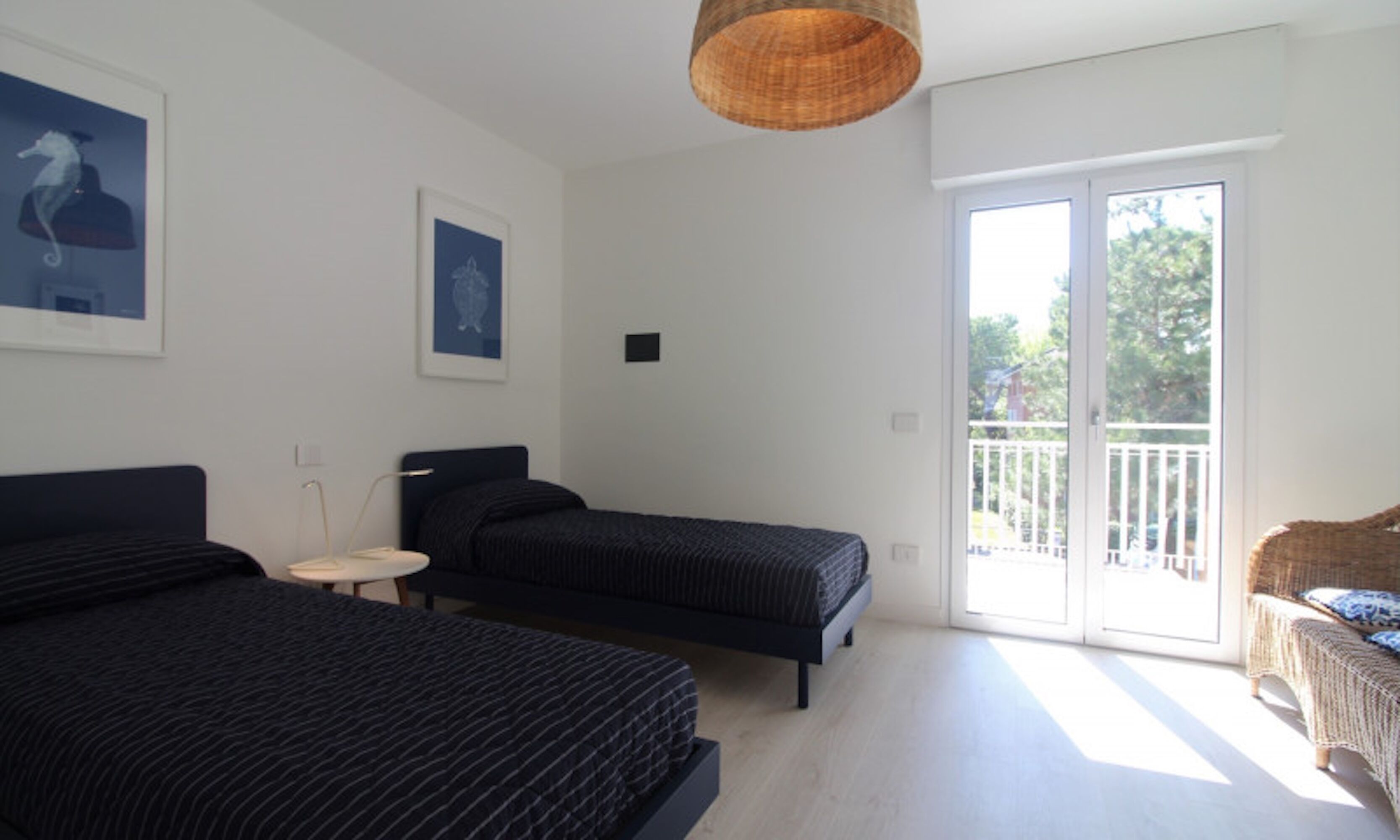 Ein Schlafzimmer mit zwei Betten, einem kleinen runden Tisch und einem Korbstuhl.