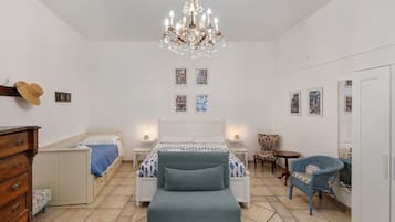 A bedroom with a bed, bedside tables, a dresser, a chair, a mirror, and a chandelier.