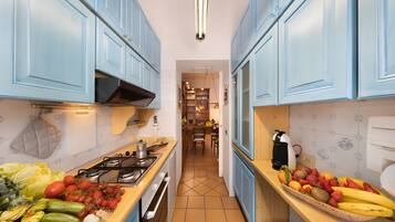 A kitchen with blue cabinets, a gas stove, and a fruit basket on the counter.