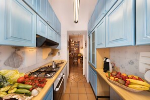 A kitchen with blue cabinets, a gas stove, and a fruit basket on the counter. - Holiday Home 'Old Fisherman House' with Wi-Fi and Air Conditioning (Sorrento)