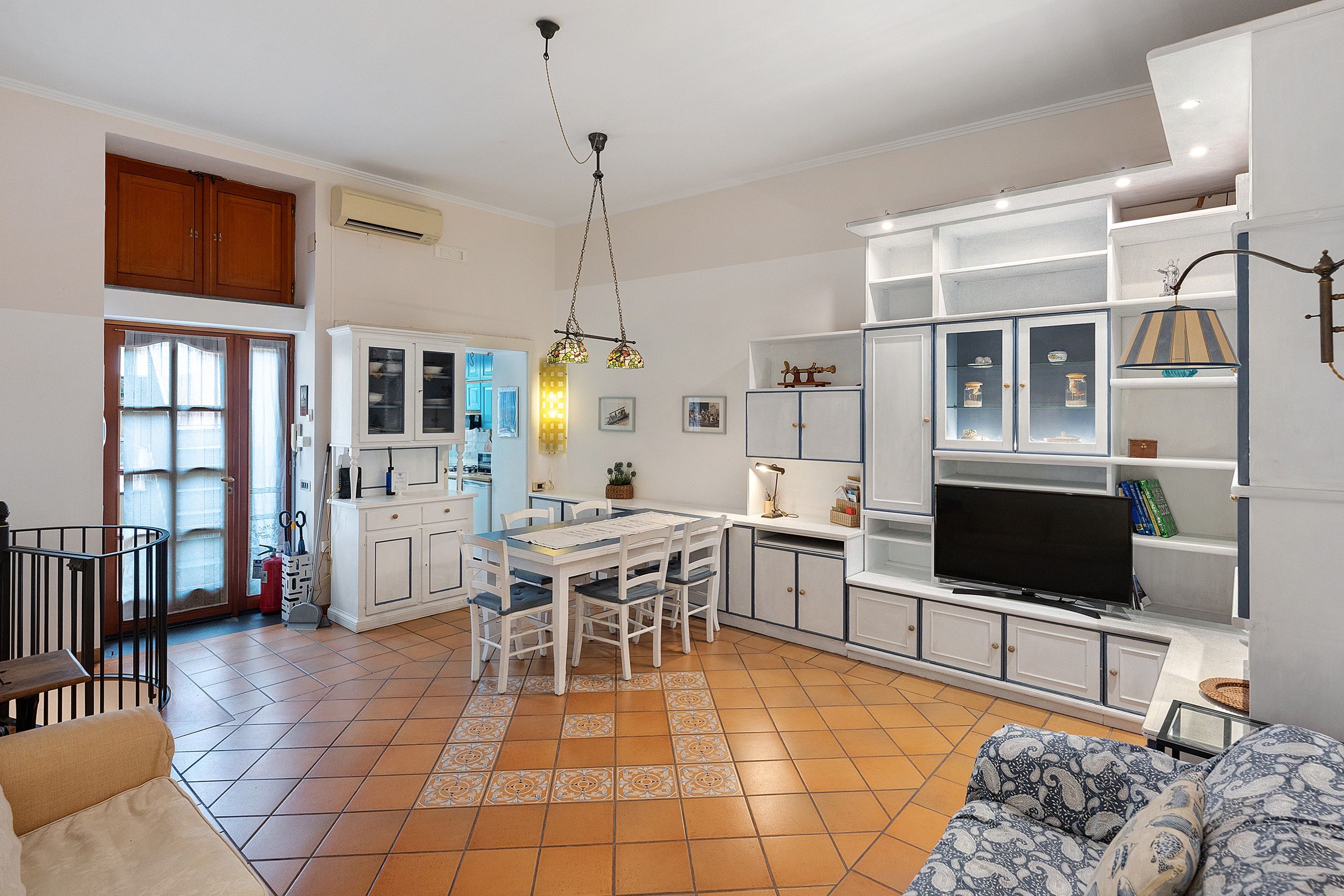 A spacious living area with a dining table, chairs, a sofa, and a television.