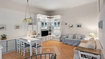 A spacious living area with a dining table, chairs, a sofa, and a television.