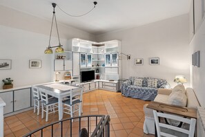 A spacious living area with a dining table, chairs, a sofa, and a television. - Holiday Home 'Old Fisherman House' with Wi-Fi and Air Conditioning (Sorrento)