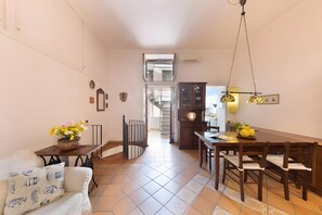 A dining area with a wooden table and chairs, a chandelier, and a staircase leading to an upper floor. - Holiday Home 'Old Fisherman House' with Wi-Fi and Air Conditioning (Sorrento)