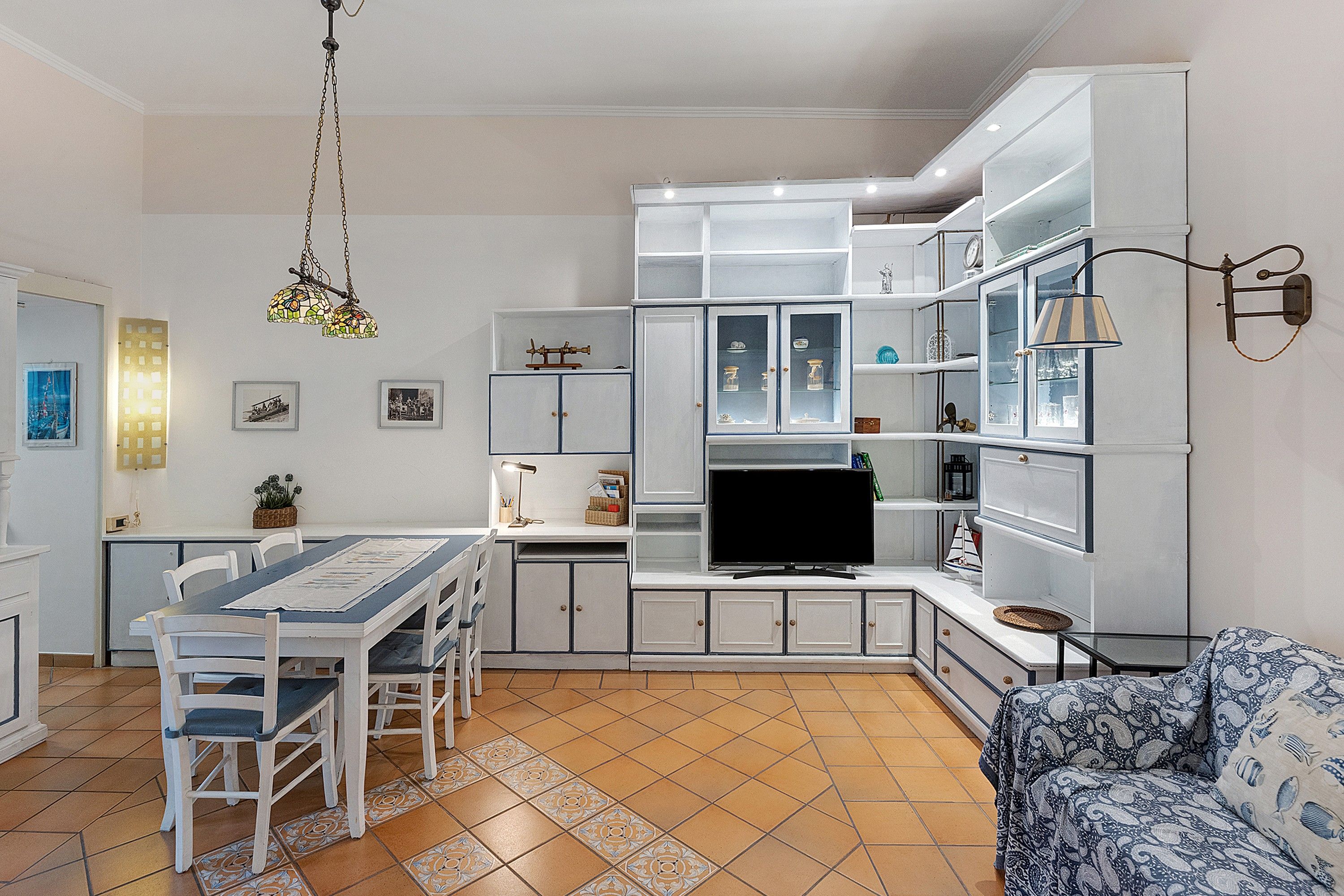 A compact kitchen with a dining area, a TV, and a sofa.