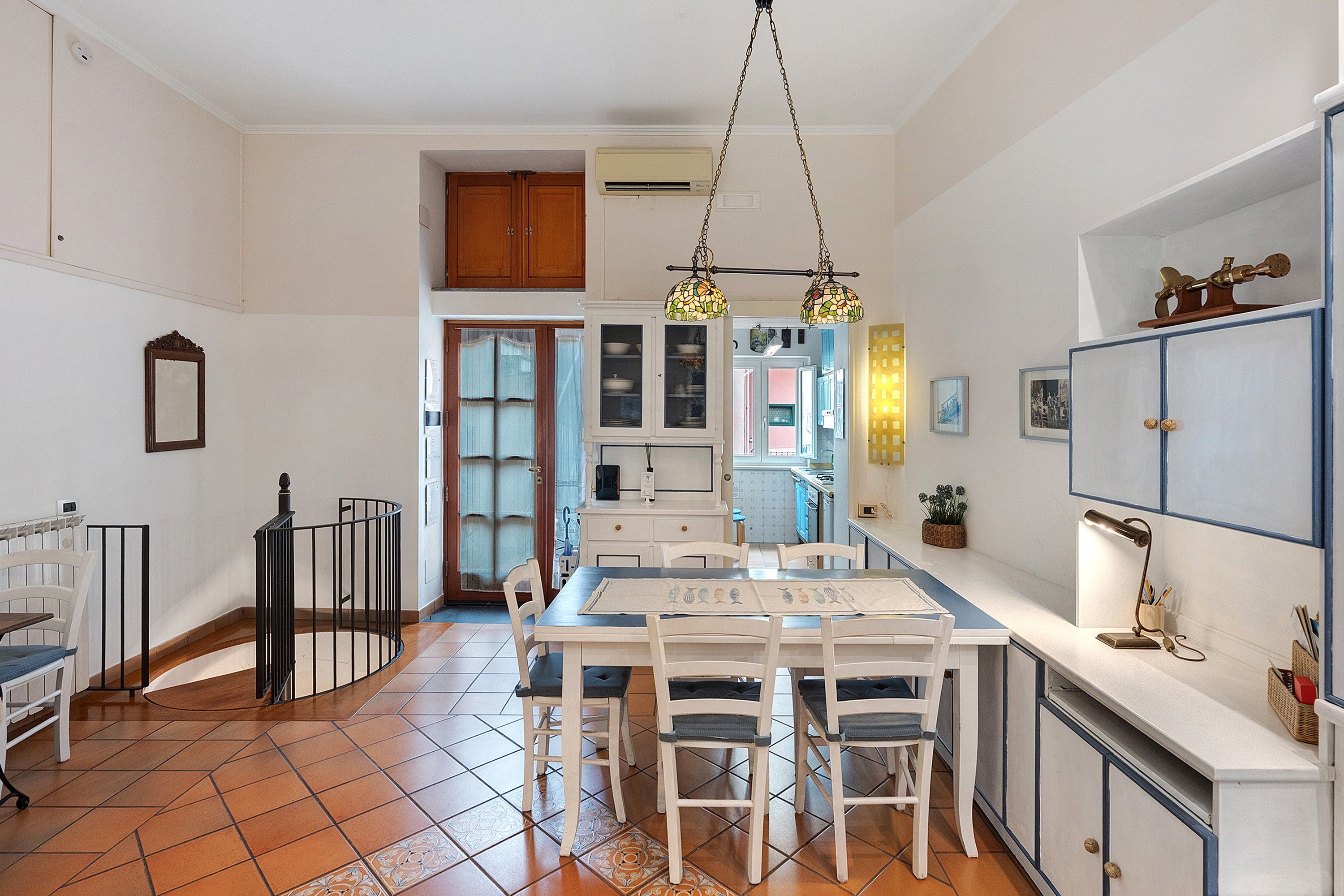 A kitchen with a dining table, chairs, and a hanging light fixture.