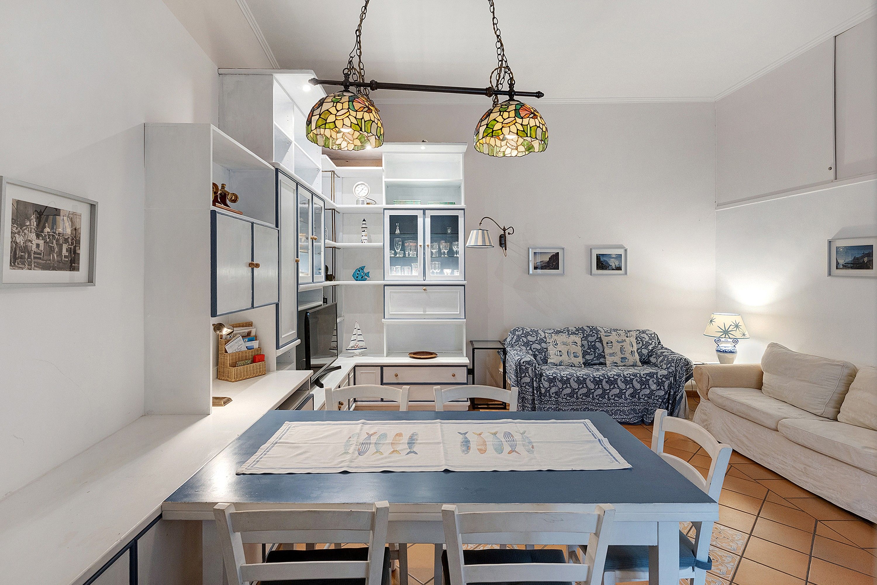 Spiseområde med bord, stole og en hængende lampe.