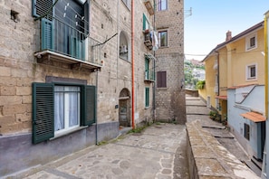 A narrow stone-paved alley between buildings with traditional shutters and a small door. - Holiday Home 'Domus Mediterranea' with Wi-Fi and Air Conditioning (Sorrento)