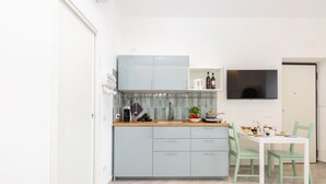 A modern kitchen with light blue cabinets, a wooden countertop, a sink, and a dining area with a white table and green chairs. - Holiday Home 'Domus Mediterranea' with Wi-Fi and Air Conditioning (Sorrento)