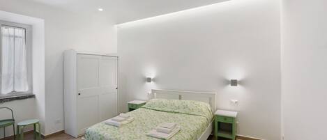 A bedroom with a bed, a wardrobe, a desk, and a chair.