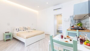 A modern bedroom with a bed, bedside tables, and a kitchenette area with a dining table and chairs. - Holiday Home 'Domus Mediterranea' with Wi-Fi and Air Conditioning (Sorrento)