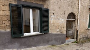 A stone building with a window with green shutters, a door with an arch, and a number '26' sign. - Holiday Home 'Domus Mediterranea' with Wi-Fi and Air Conditioning (Sorrento)