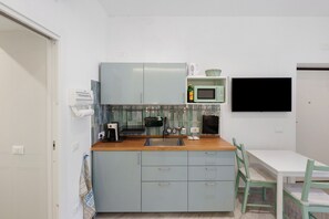A compact kitchen with a sink, a microwave, and a coffee maker. There is a small dining area with a table and chairs. - Holiday Home 'Domus Mediterranea' with Wi-Fi and Air Conditioning (Sorrento)
