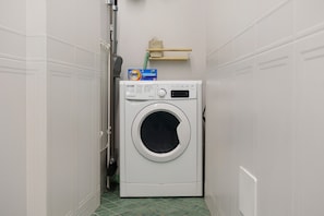 A compact, white washing machine in a narrow hallway with tiled flooring. - Holiday Home 'Domus Mediterranea' with Wi-Fi and Air Conditioning (Sorrento)