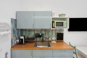 A compact kitchen with a wooden countertop, a built-in microwave, and a coffee maker. - Holiday Home 'Domus Mediterranea' with Wi-Fi and Air Conditioning (Sorrento)
