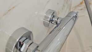 A bathroom with a glass shower enclosure, chrome fixtures, and marble walls. - La Bastide Foch – Premium Appart’Hotel City Center (Salon-de-Provence)