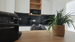 A compact kitchen with a microwave, a sink, and a potted plant on a wooden table. - La Bastide Foch – Premium Appart’Hotel City Center (Salon-de-Provence)