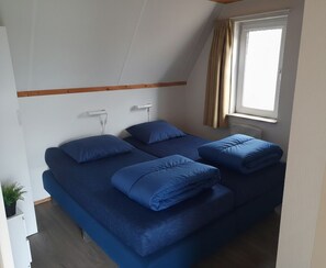 Una habitación con dos camas, una ventana con cortinas y un radiador.