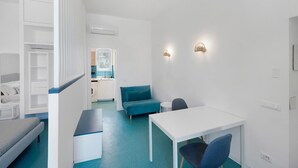 Una habitación moderna y minimalista con un escritorio blanco, un sofá azul y una pequeña mesa.