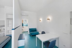 A modern, minimalist room with a white desk, blue sofa, and a small table. - Apartment 'Annabella' with Sea View, Wi-Fi and Air Conditioning (Sorrento)