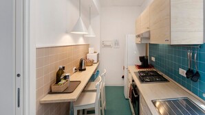Cocina compacta con estufa a gas, microondas y pileta. Cuenta con alacenas de madera y un salpicadero de azulejos azules.