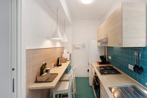 A compact kitchen with a gas stove, a microwave, and a sink. There are wooden cabinets and a blue tiled backsplash. - Apartment 'Annabella' with Sea View, Wi-Fi and Air Conditioning (Sorrento)