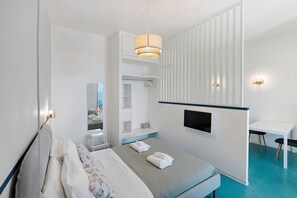 A hotel room with a bed, a desk, a TV, a wardrobe, and a bathroom mirror. - Apartment 'Annabella' with Sea View, Wi-Fi and Air Conditioning (Sorrento)