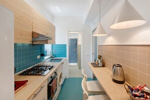 A compact kitchen with a gas stove, a washing machine, and a coffee machine. - Apartment 'Annabella' with Sea View, Wi-Fi and Air Conditioning (Sorrento)