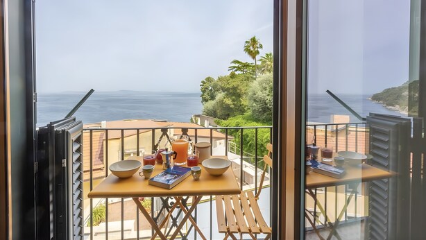 Un balcón con una mesa dispuesta para el desayuno, con vista al mar.