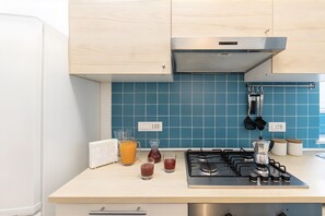 A modern kitchen with a gas stove, a coffee maker, and a blue tiled backsplash. - Apartment 'Annabella' with Sea View, Wi-Fi and Air Conditioning (Sorrento)