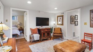 A room with a bed, a TV, a wooden cabinet, a chair, and a red chair.