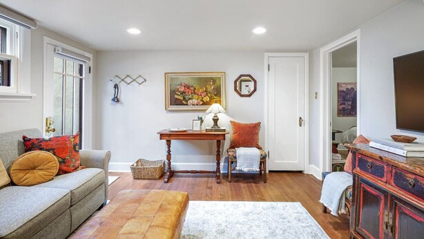 A living room with a sofa, a table, a chair, a television, and a cabinet.