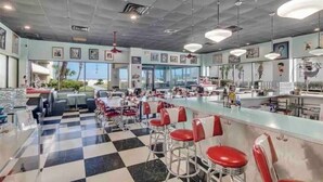 Un restaurante con suelo a cuadros, taburetes rojos y una larga barra.