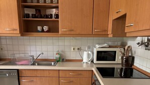 A kitchen with wooden cabinets, a microwave, a dishwasher, and a tiled backsplash.