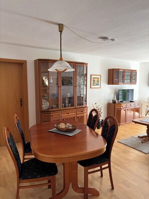 A dining room with a wooden table and chairs, a cabinet with glass doors, and a ceiling fan. - Enjoy a vacation on the edge of Saxon Switzerland (Dürrröhrsdorf-Dittersbach)