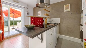 Une cuisine dotée d’un four encastré, d’une fenêtre avec un parapluie et d’une vue sur l’extérieur.