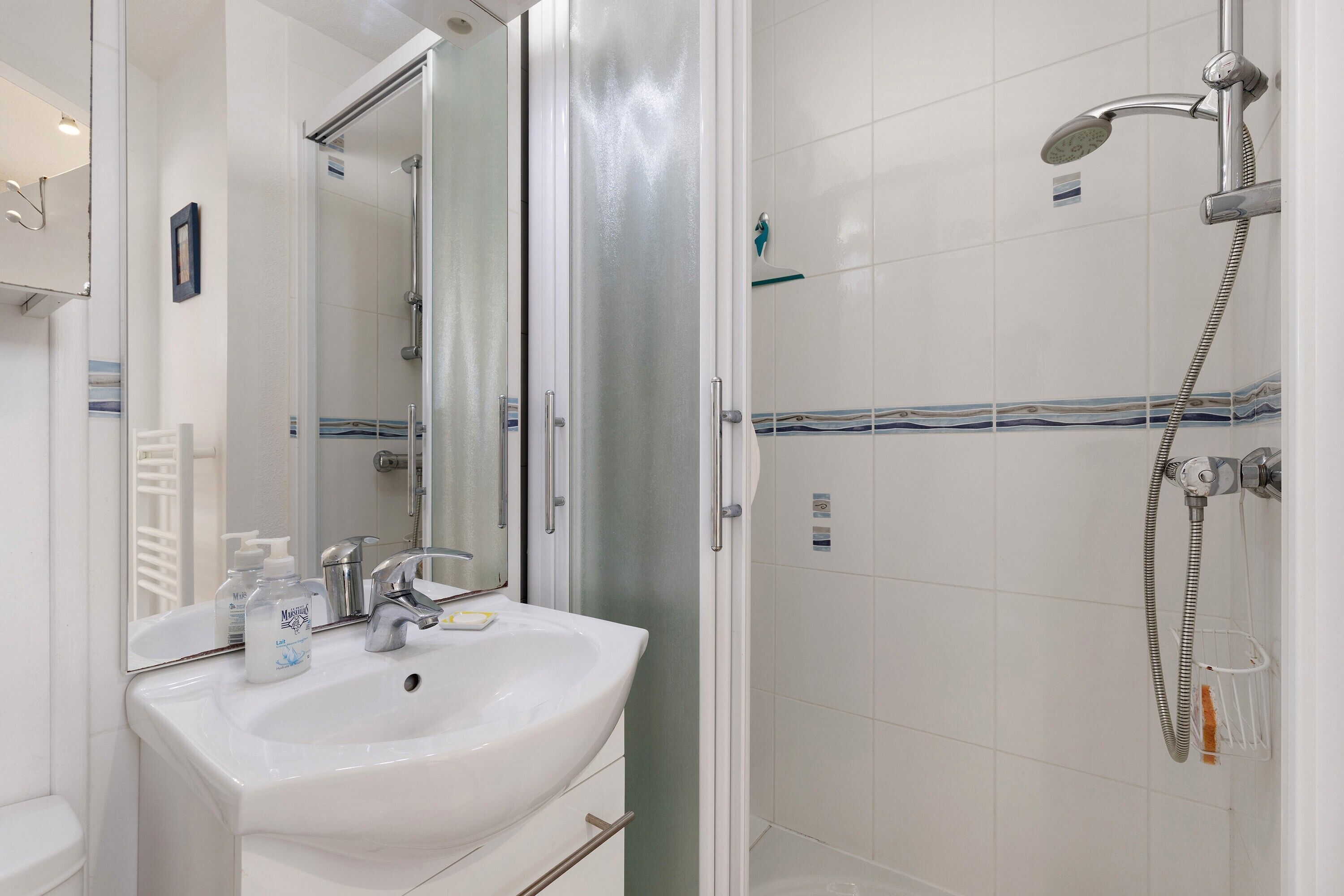 Ein Badezimmer mit einem weißen Waschbecken, Spiegel und Dusche.