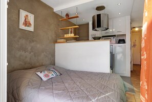 Ein kleines Zimmer mit Bett, einer Küchenzeile und einer Essecke.