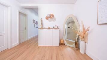 A hallway with a white door, a white cabinet, a mirror, and a wall-mounted decorative piece.