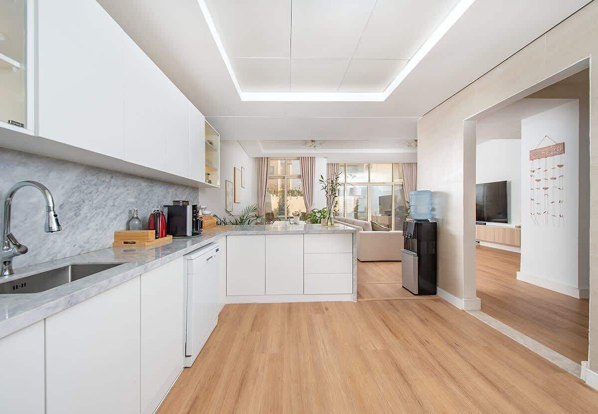A modern kitchen with white cabinetry, a marble countertop, and a central island.