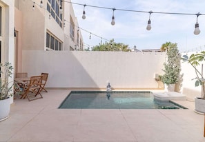 A swimming pool with a white wall, a small Buddha statue, and string lights. - Al Furjan Villa WPrivate Pool & Gym Near Marina (Dubai)