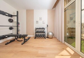 Een sportschool thuis met een bankdrukapparaat, een gewichtrek, gewichtsschijven en een medicine ball.