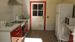 A kitchen with a stove, microwave, and refrigerator. - Historic Post House Gîte, 8 Bedrooms (Les Rousses)