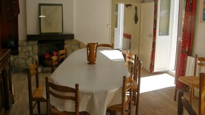 A dining room with a stone fireplace, a large table, and wooden chairs. - Historic Post House Gîte, 8 Bedrooms (Les Rousses)