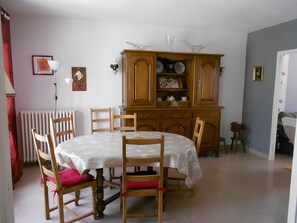 A dining area with a round table, wooden chairs, a cabinet with decorative items, and a radiator. - Country House for 7 People (Guérigny)