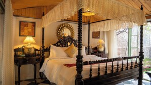 A four-poster canopy bed with a checkered floor, a mirror with a sunburst design, and a lamp on a nightstand. - Bhanpur Haveli | Hidden Luxury Haveli Amid Greenery & Peace (Jamwa Ramgarh)
