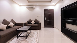 A modern living room with a sofa set, a coffee table, a flat-screen TV, and an air conditioning unit. - Deyala Serviced Apartments 6 (Riyadh)