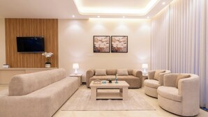A modern living room with a sofa set, a coffee table, and a TV mounted on a wooden panel wall. - Deyala Serviced Apartments 6 (Riyadh)