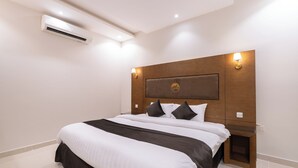 A modern hotel room with a large bed, a wooden headboard, and a wall-mounted air conditioner. - Deyala Serviced Apartments 6 (Riyadh)